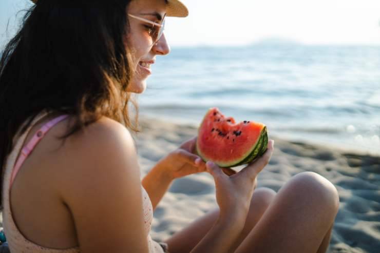 ragazza che mangia anguria sulla spiaggia