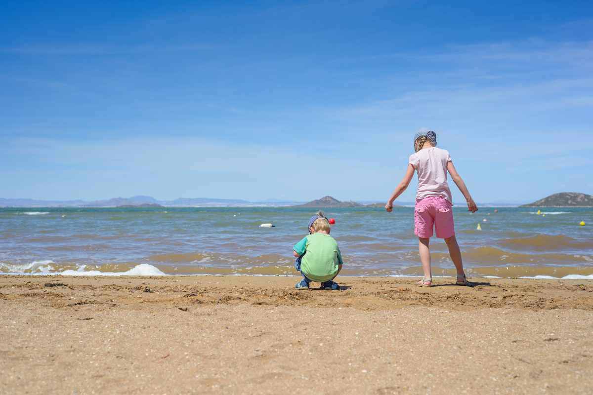 due bambini giocano su spiaggia mare sfondo