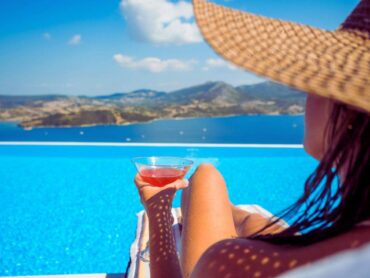 ragazza al mare con cappello e drink in mano