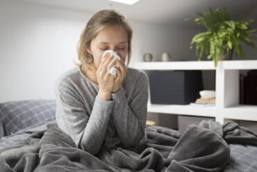 Ragazza si soffia il naso a letto